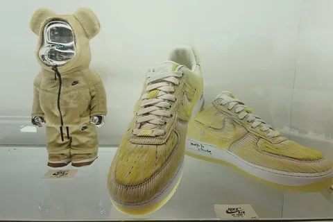Vitrine avec ours en peluche et basket jaune Nike exposée.