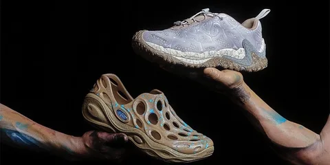 Deux chaussures en équilibre tenues par des bras peints sur fond noir.