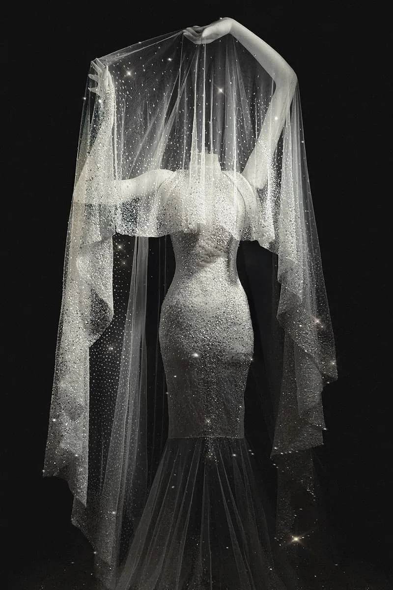 Mannequin avec robe saphir et voile transparent éblouissant.