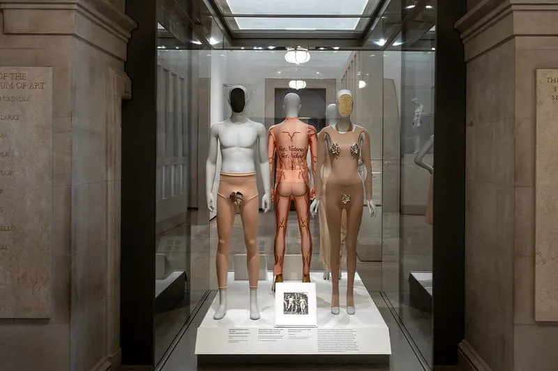 Trois mannequins de couleur différente exposés dans une vitrine de musée.
