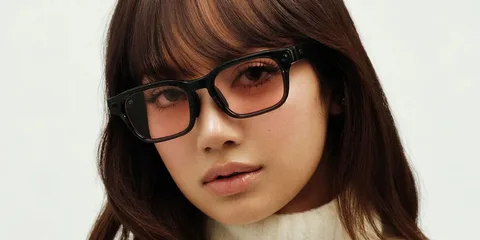 Femme aux lunettes carrées et pull blanc.