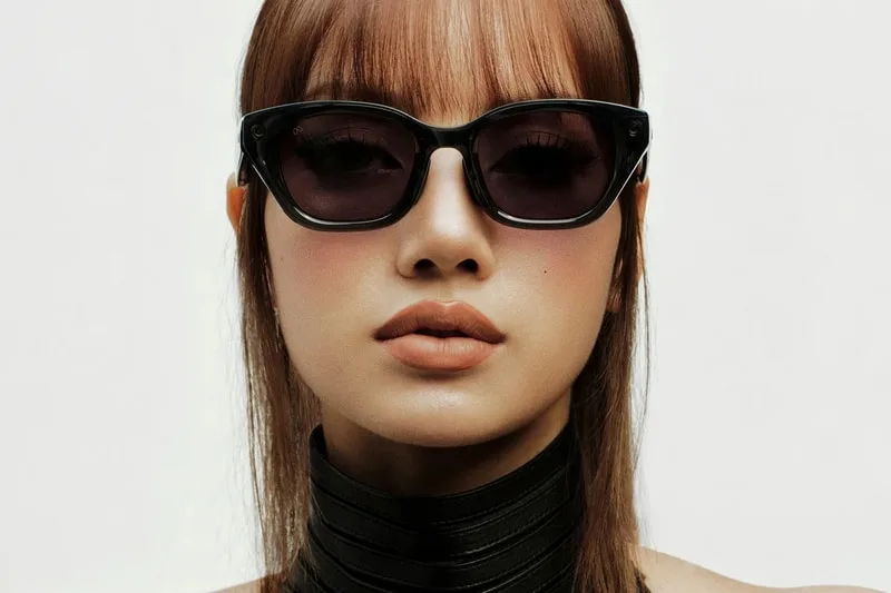 Femme avec lunettes de soleil noires et frange nette, expression neutre.