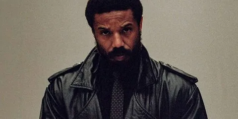 Homme noir en manteau en cuir, regard intense.