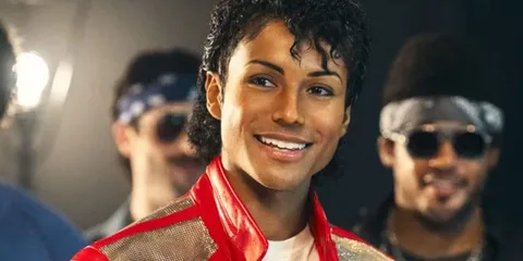 Personne souriante en veste rouge, cheveux bouclés, style rétro.