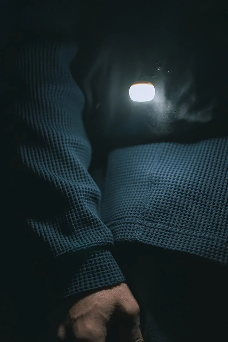 Main en pull bleu foncé éclairée par une petite lumière.