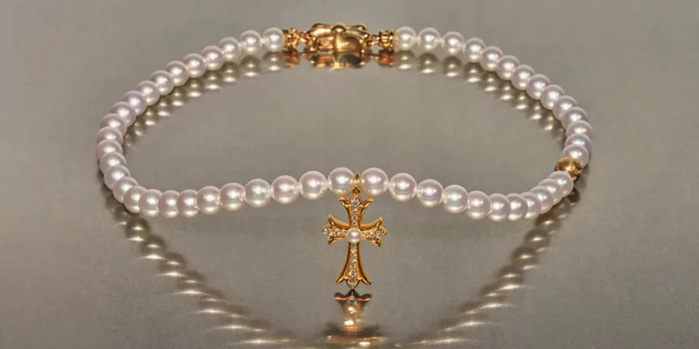Bracelet de perles avec croix en or et diamants.