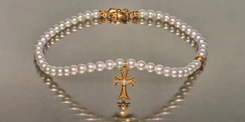 Bracelet de perles avec croix en or et diamants.