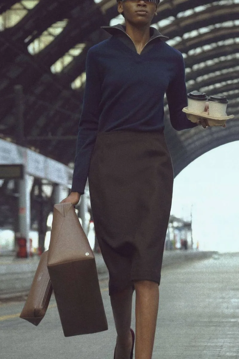 Femme élégante portant un café dans une gare.