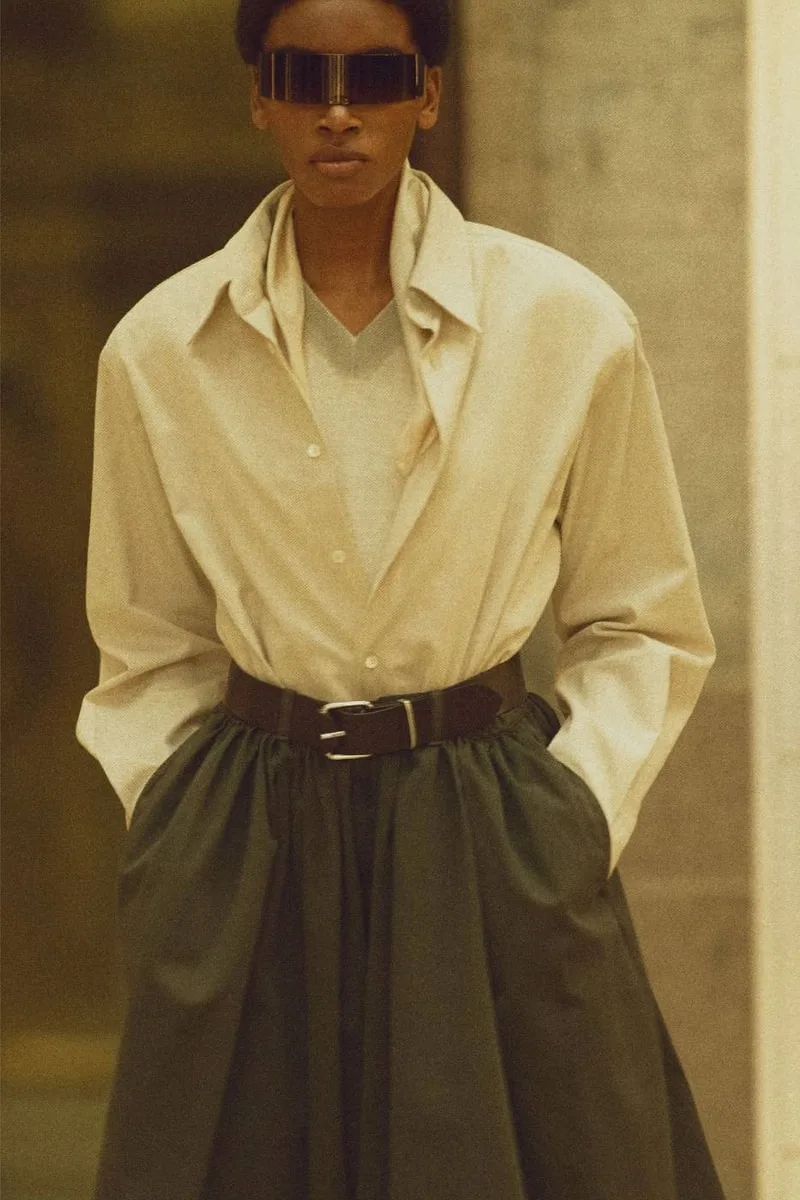 Personne avec veste beige et jupe verte, lunettes futuristes
