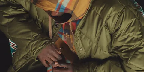 Personne en veste verte et sweat à capuche rayé, vue de haut.