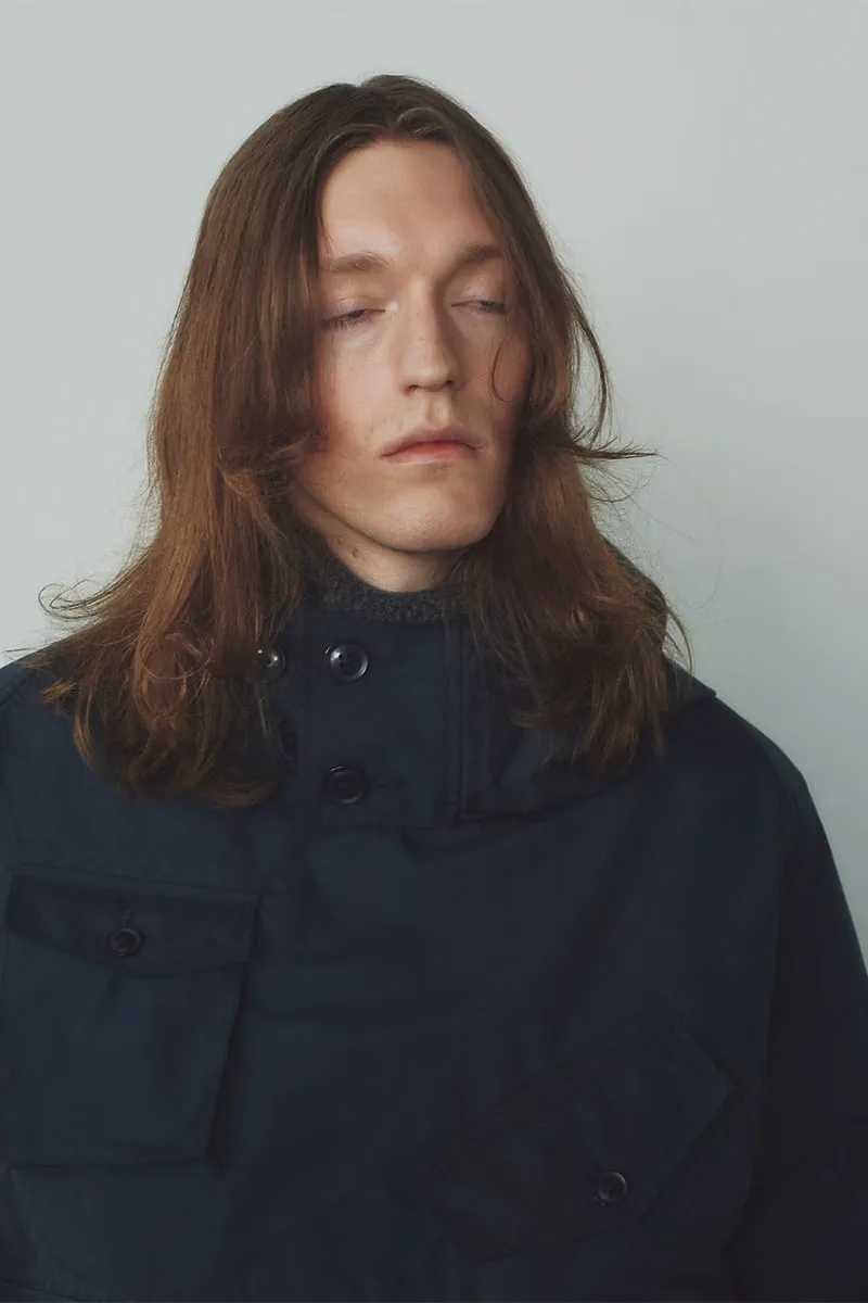 Homme aux cheveux longs, veste noire, yeux fermés.