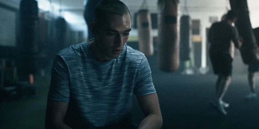 Homme en maillot de sport dans une salle de gym avec sacs de frappe.