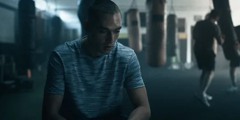 Homme en maillot de sport dans une salle de gym avec sacs de frappe.
