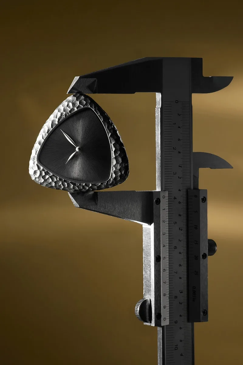 Montre en forme de triangle avec une règle métallisée, fond doré.