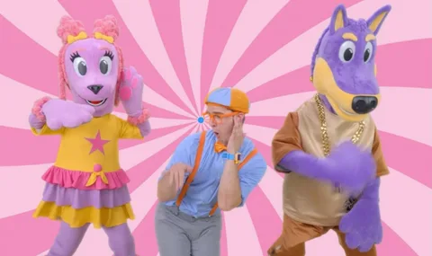 Personnage en costume coloré avec deux mascottes sur fond rose.