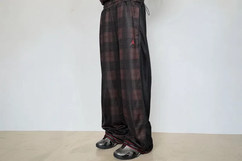 Pantalon ample foncé avec logo rouge sur le côté.