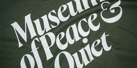 Texte blanc « Musée de la paix & Quiet » sur fond vert sombre texturé.