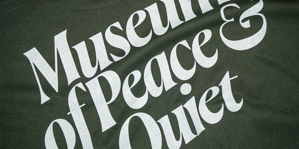 Texte blanc « Musée de la paix & Quiet » sur fond vert sombre texturé.