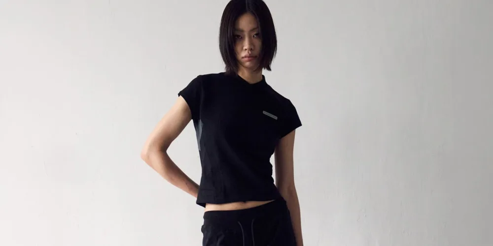Femme avec un t-shirt noir et pantalon, pose décontractée.