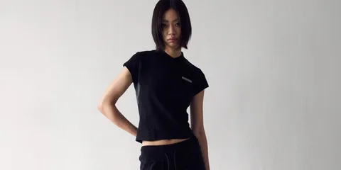 Femme avec un t-shirt noir et pantalon, pose décontractée.