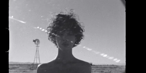 Personne aux cheveux bouclés devant un paysage désertique.