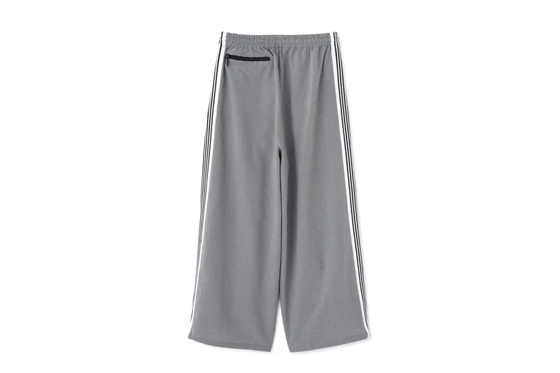 Pantalon gris à large jambe avec rayures latérales blanches.