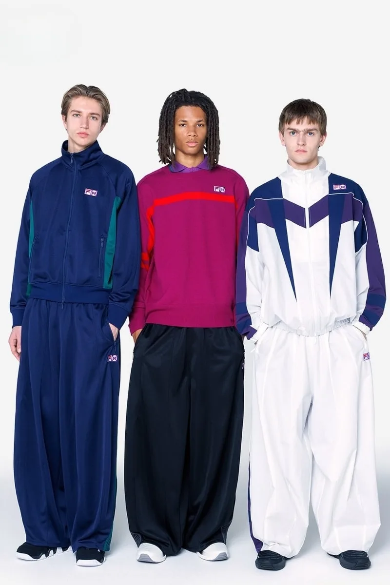Trois hommes portant des survêtements amples aux couleurs variées.