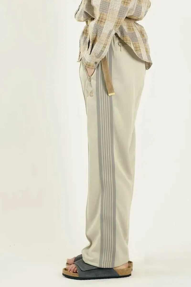 Personne portant un pantalon beige avec des rayures et sandales.