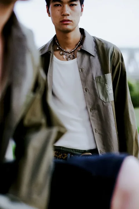 Jeune homme en chemise verte avec collier, arrière-plan flou