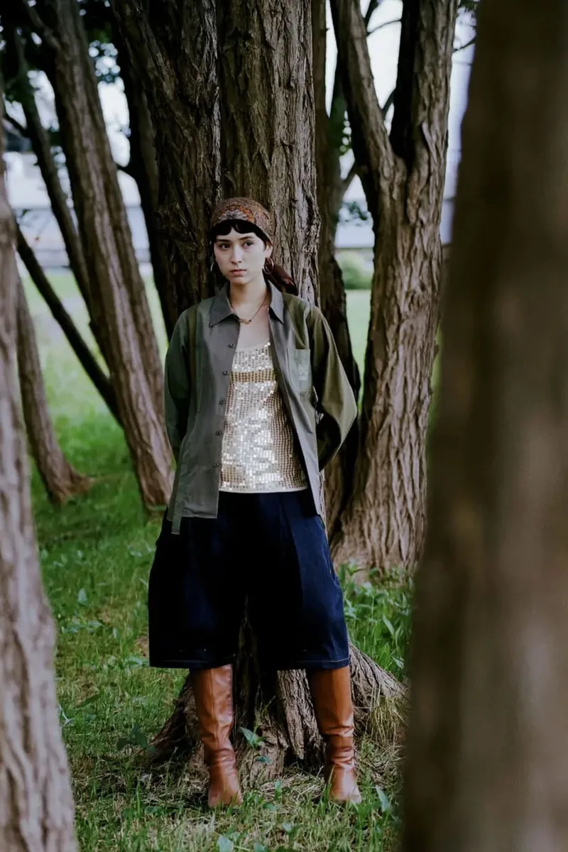 Personne avec tenue élégante devant arbres dans parc.