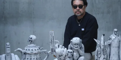 Homme assis avec sculptures artistiques énigmatiques sur une table.