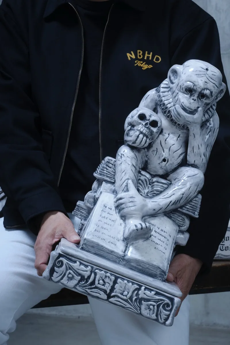 Sculpture de singe avec un crâne, assis sur des livres.