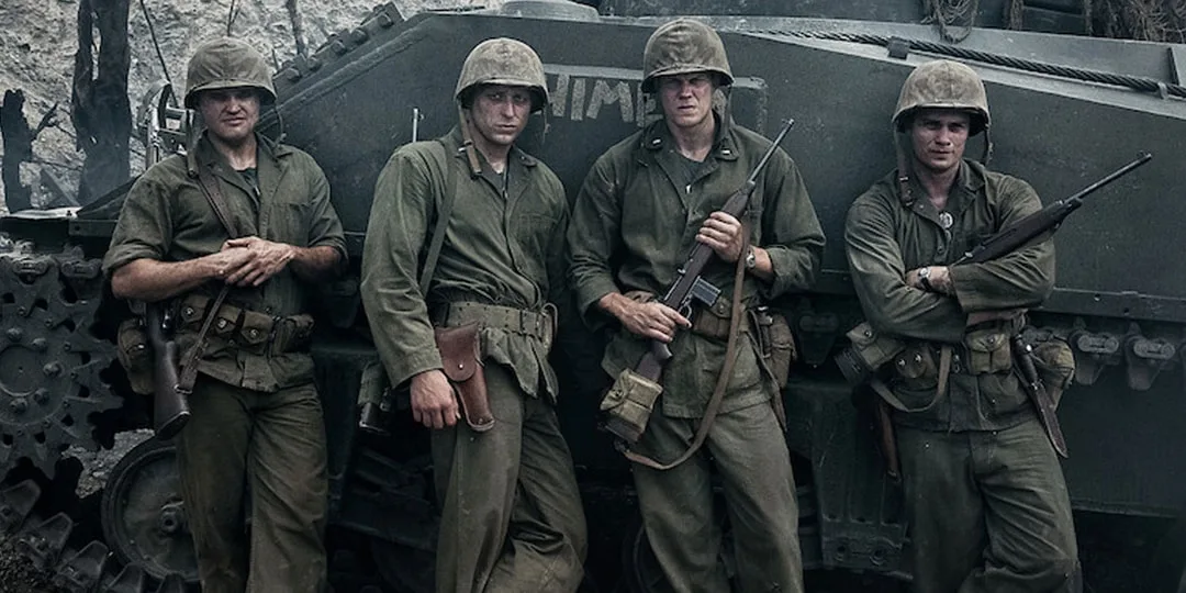 Quatre soldats en uniforme devant un char.