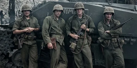 Quatre soldats en uniforme devant un char.