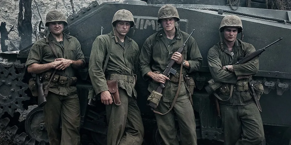 Quatre soldats en uniforme devant un char.