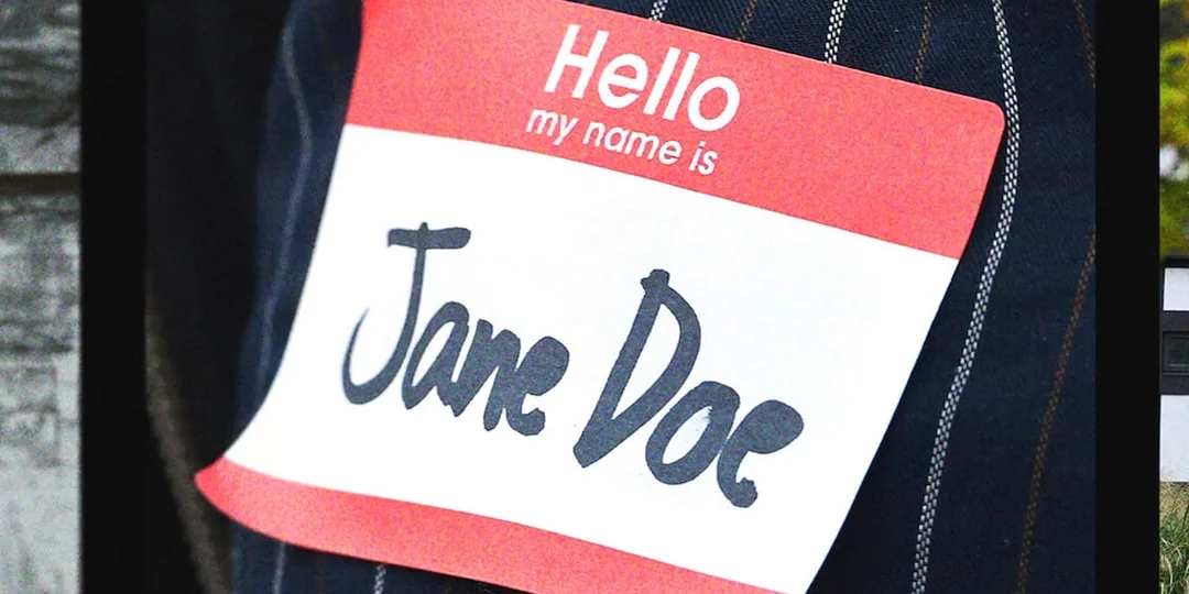 Badge nominatif rouge et blanc portant le nom « Jane Doe » sur une veste en jean.