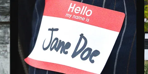 Badge nominatif rouge et blanc portant le nom « Jane Doe » sur une veste en jean.