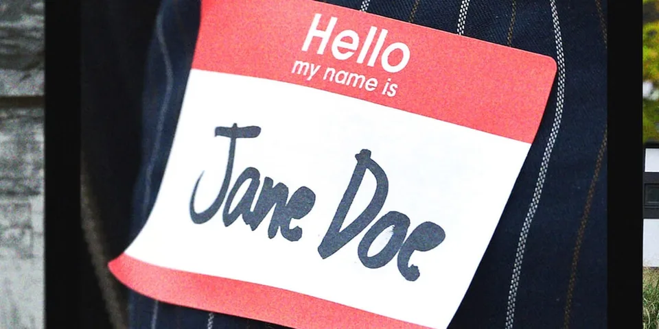 Badge nominatif rouge et blanc portant le nom « Jane Doe » sur une veste en jean.
