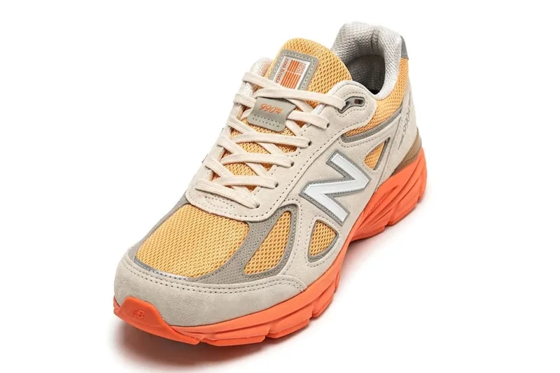 Chaussure de sport beige et orange avec logo sur le côté.