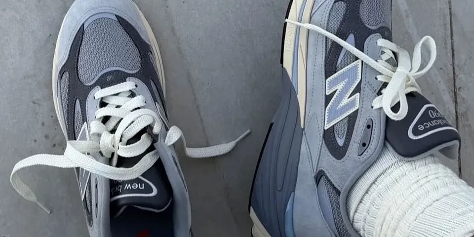 Deux chaussures New Balance grises sur le sol.
