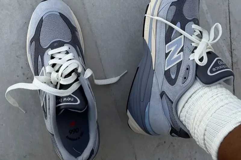 Chaussures de sport New Balance grises sur fond de pierre grise.