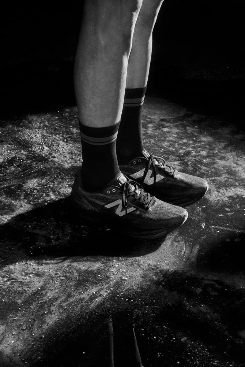 Jambes humaines avec chaussures de sport sur sol humide en noir et blanc.