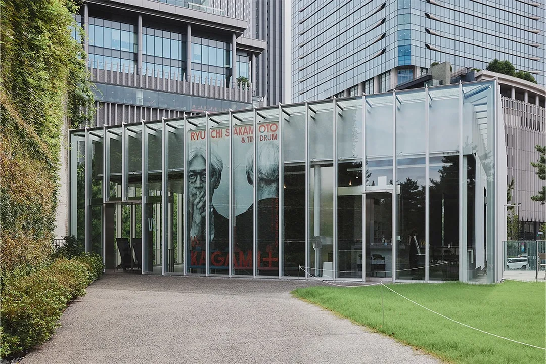 Bâtiment moderne avec affiches en verre et pelouse verte à l'avant.