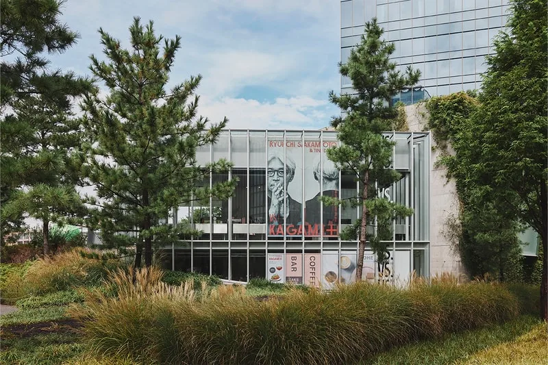 Bâtiment moderne avec affiches et arbres environnants.
