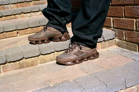 Homme portant des baskets marron sur des marches en brique