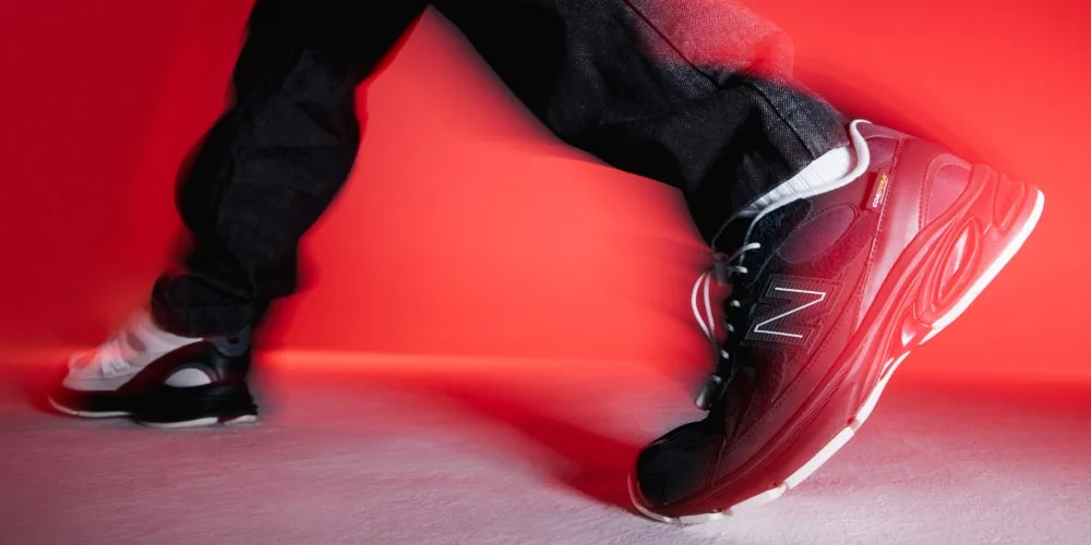 Personne marche en baskets rouges et noires sur fond rouge dynamique.