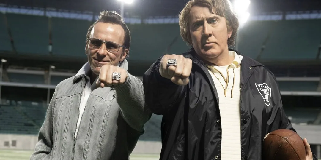 Deux hommes avec des bagues de championnat sur un terrain de football.