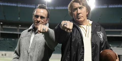 Deux hommes avec des bagues de championnat sur un terrain de football.