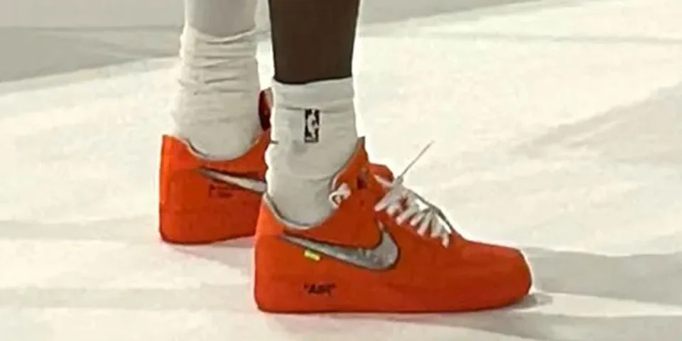 Chaussures orange avec logo Nike, portées avec des chaussettes blanches NBA.