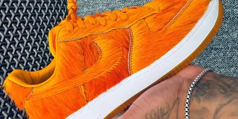 Chaussure orange en fourrure avec semelle blanche, en gros plan.